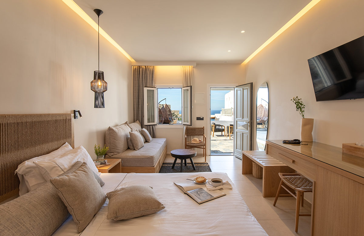 Bright interior with bed, sitting area and balcony leading to Aegean Sea view at Damianos Hotel Mykonos