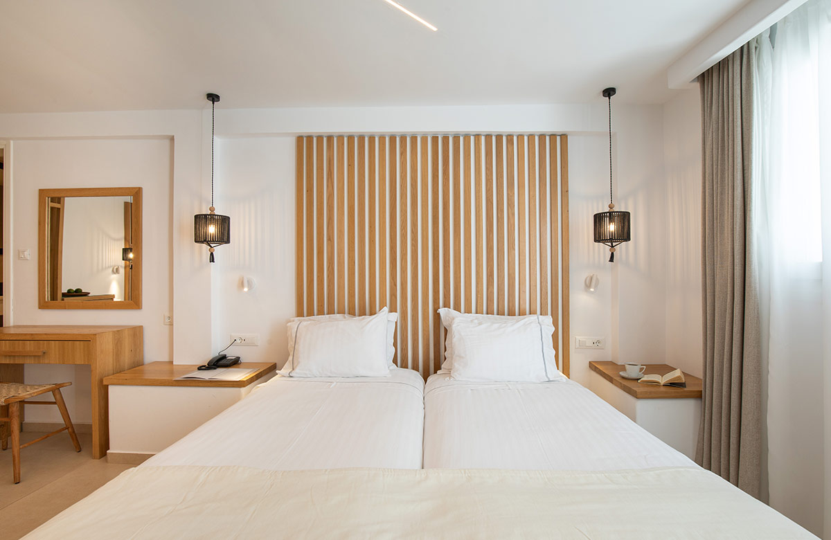 Twin beds with wooden headboard and pendant lighting in Triple Standard Room at Damianos Hotel in Mykonos Town