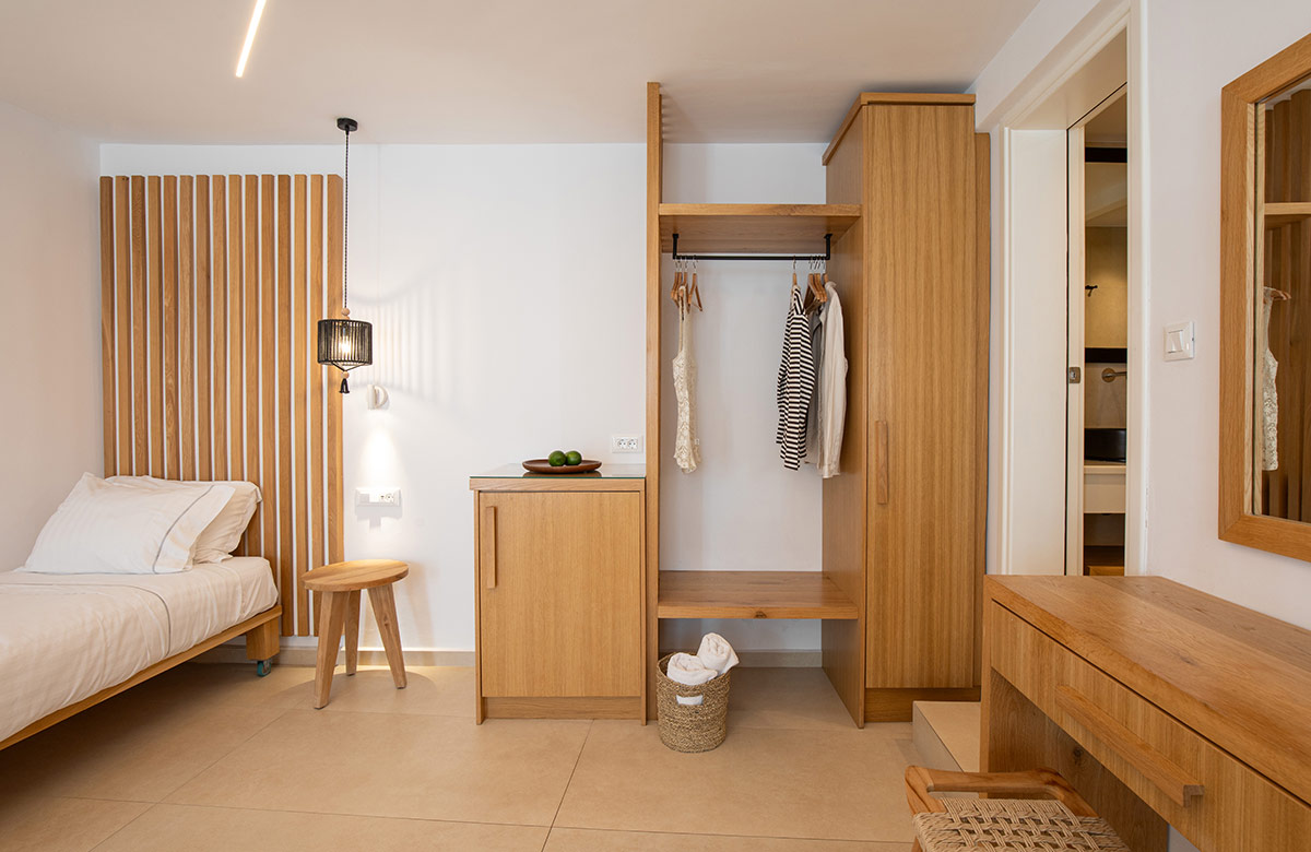 Open wardrobe and dressing area with natural wood finishes in Triple Standard Room at Damianos Hotel Mykonos Town