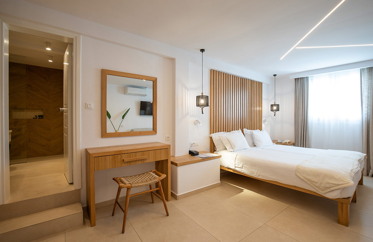 Bright bedroom with wooden details and direct access to modern bathroom in Triple Standard Room at Damianos Hotel Mykonos Town