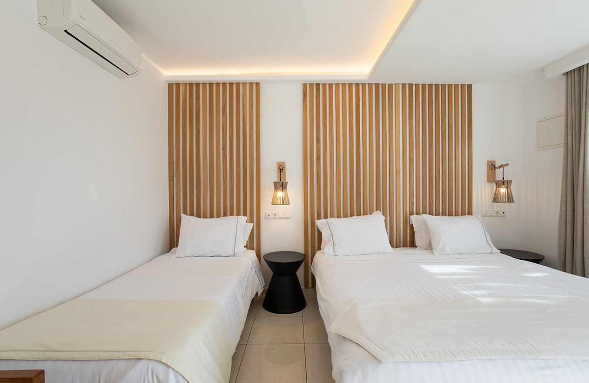 Twin and double bed arrangement with wooden headboards in Mykonos Town hotel room