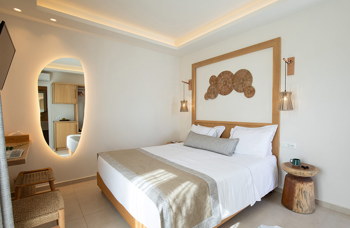 Cozy hotel room in Mykonos Town with double bed, earthy tones and outdoor patio seating area at Damianos Hotel