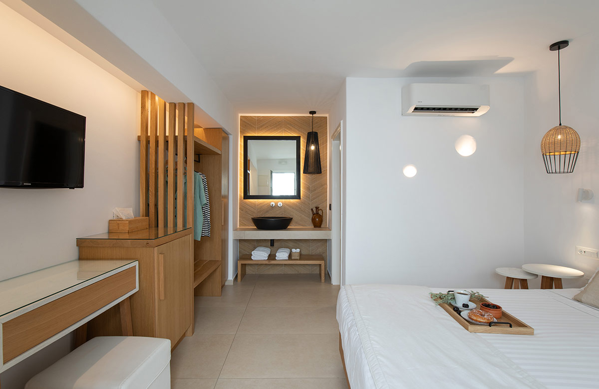 Interior of hotel room in Mykonos Town featuring wooden details, open wardrobe, vanity area and modern amenities at Damianos Hotel