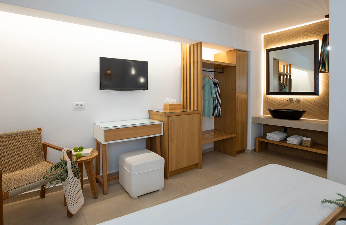Hotel room in Mykonos Town with open wardrobe, illuminated vanity mirror and modern furnishings at Damianos Hotel