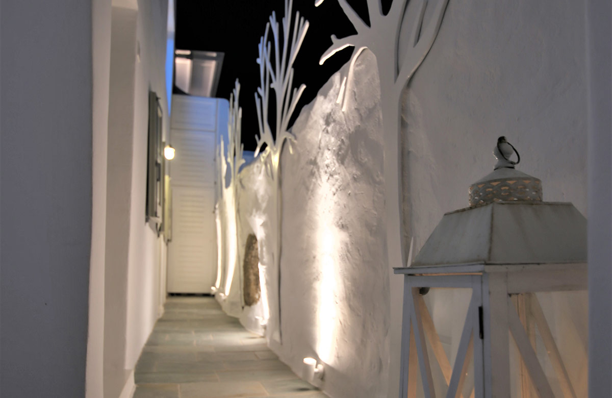Evening walkway at Damianos Hotel in Mykonos Town with whitewashed walls, soft lighting and decorative lanterns