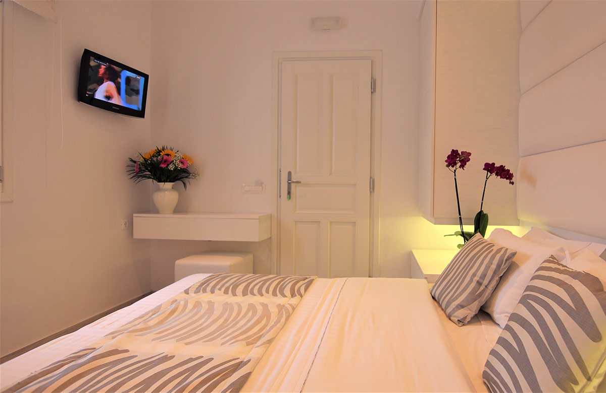 Cozy hotel room in Mykonos Town at Damianos Hotel with double bed, soft lighting and minimalist white interior design