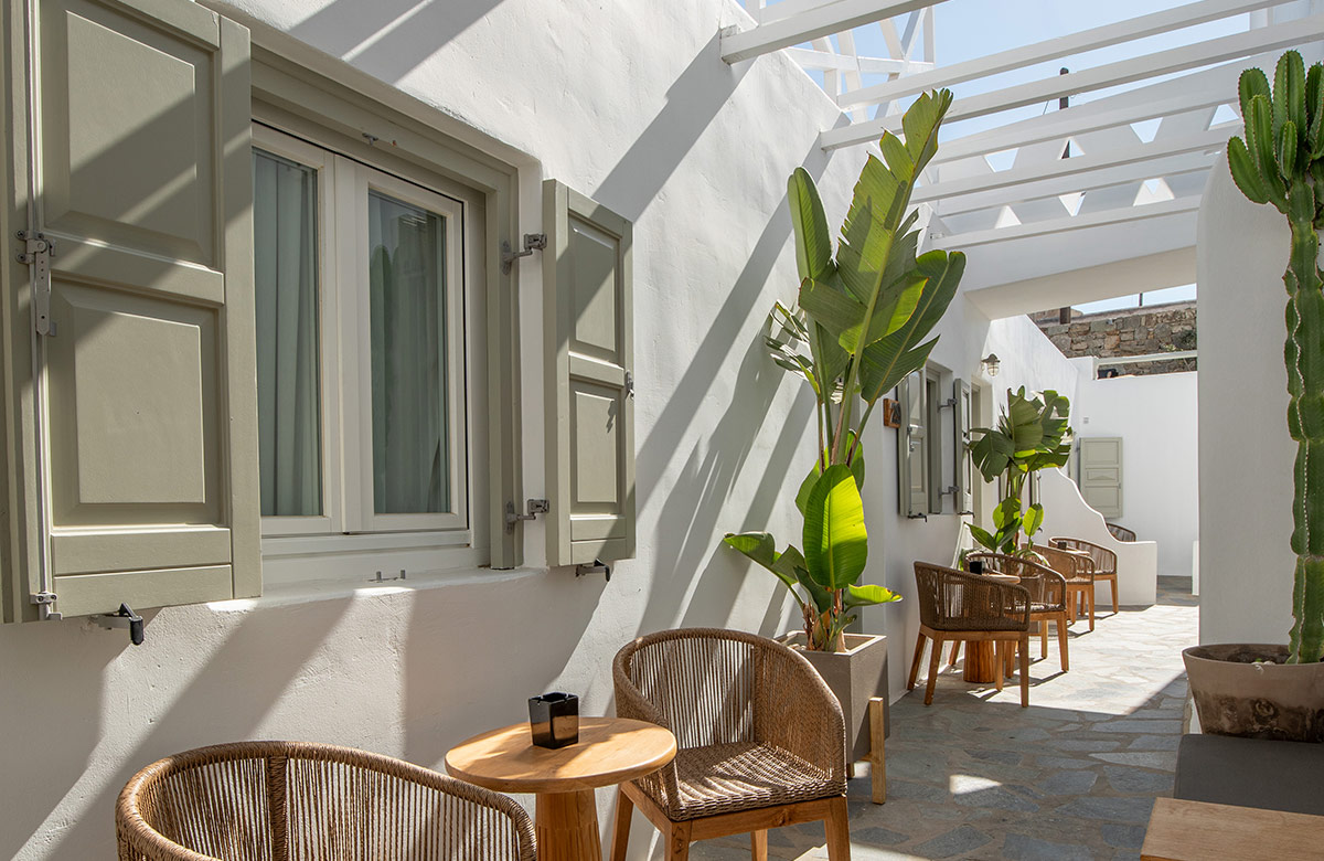 Outdoor patio area of hotel room in Mykonos Town at Damianos Hotel with private seating, whitewashed walls and natural sunlight
